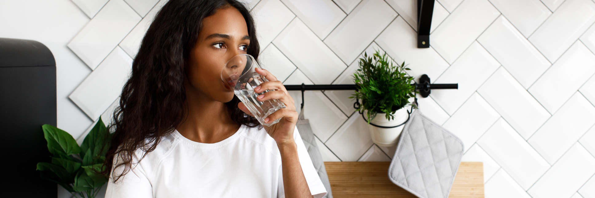 Girl stands on the kitchen and drinks water